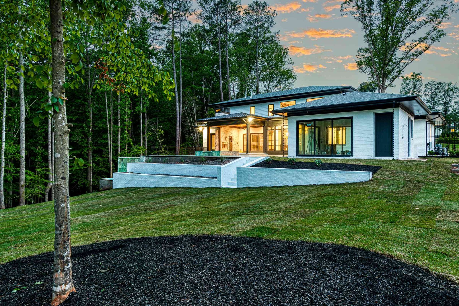 Rear of luxury home glowing at dusk by Shail Construction in Raleigh NC